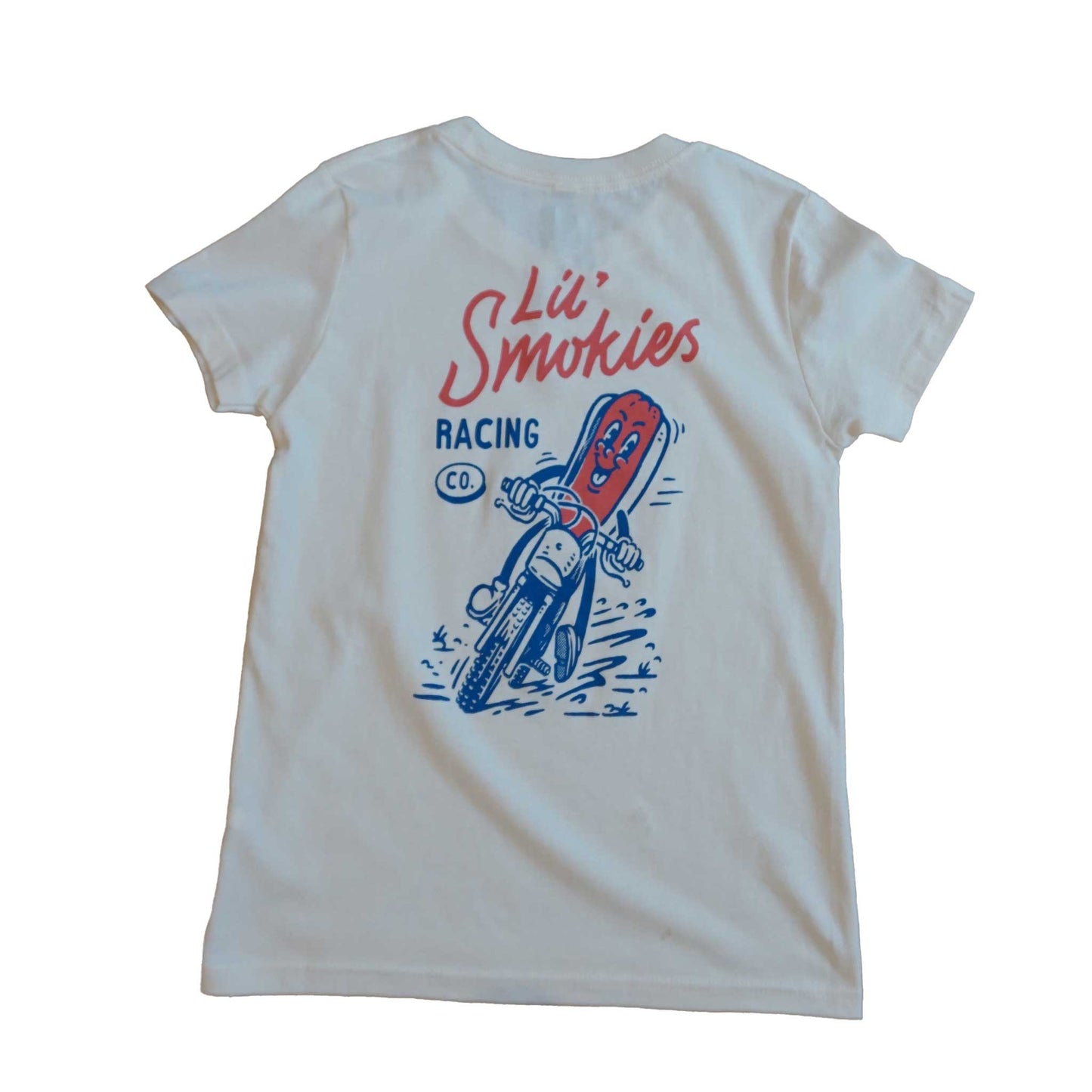 Youth tshirt in short sleeve ivory color. Lil Smokies Racing branding with original design of a hotdog in a bun riding a motorcycle. The graphic is a cartoon image in a faded red and soft blue ink. The hotdog is smiling as dirt is flying up.