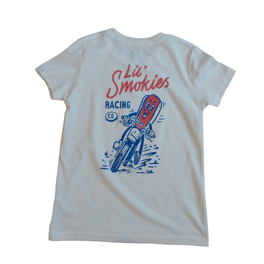 Youth tshirt in short sleeve ivory color. Lil Smokies Racing branding with original design of a hotdog in a bun riding a motorcycle. The graphic is a cartoon image in a faded red and soft blue ink. The hotdog is smiling as dirt is flying up.