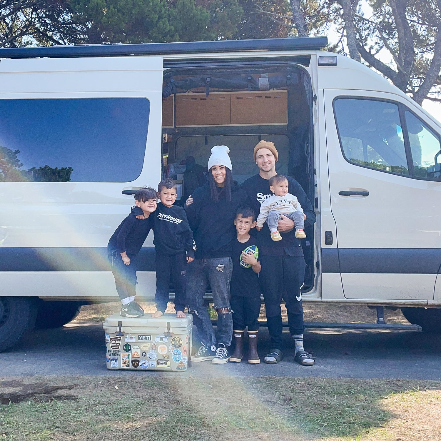 The family that races together. Standing in front of there Mercedes Sprinter van posing for a photo. Motocross and dirt bikes are parked at home.