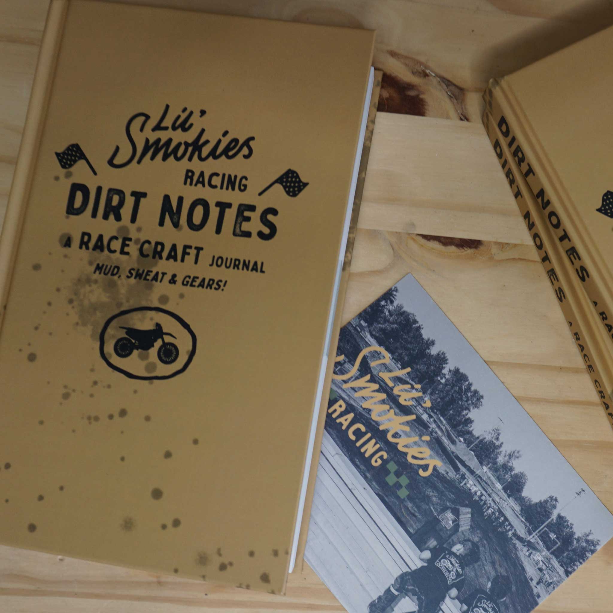 Motocross racer's planner journal featuring a vibrant cover with a dirt bike graphic, resting on a rustic wooden desk." Ecommerce SEO optimized alt text: "Stay organized and inspired with this motocross racer's planner journal, showcasing a dynamic dirt bike graphic on the cover. Ideal for dirt bike enthusiasts seeking to plan their races and track their progress. Order now for your next adrenaline-fueled adventure! Dirt Notes, a race craft journal.