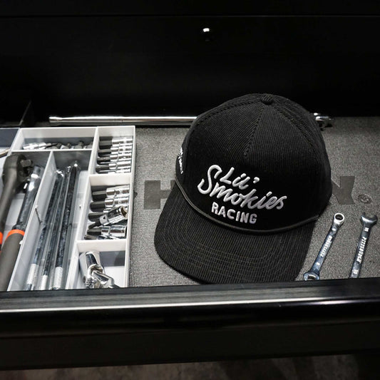 image of the Lil Smokies Racing hat in a tool box drawer, Corduroy black 5 panel hat with white Lil Smokies Racing stitching.