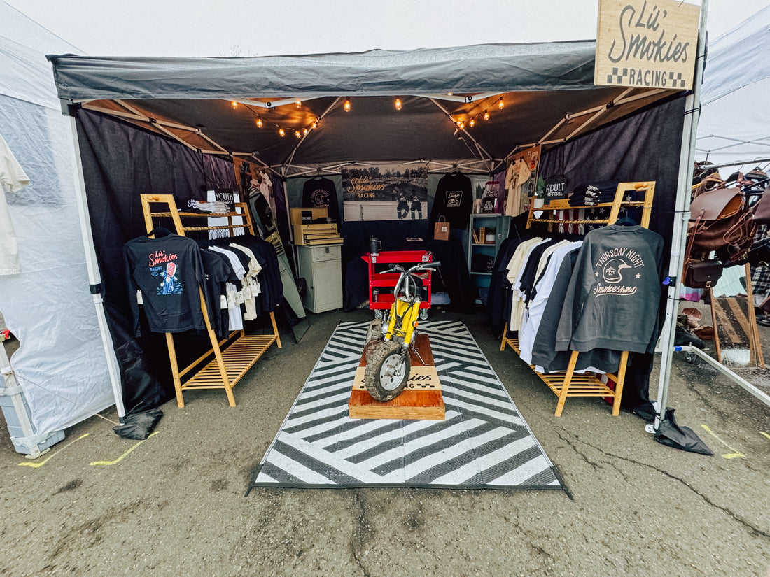 Vendor booth setup for Lil Smokies Racing including adult and youth apparel as well as a 1969 Honda Monkey in canary yellow. Apparel for both adult and youth inspired by motocross 