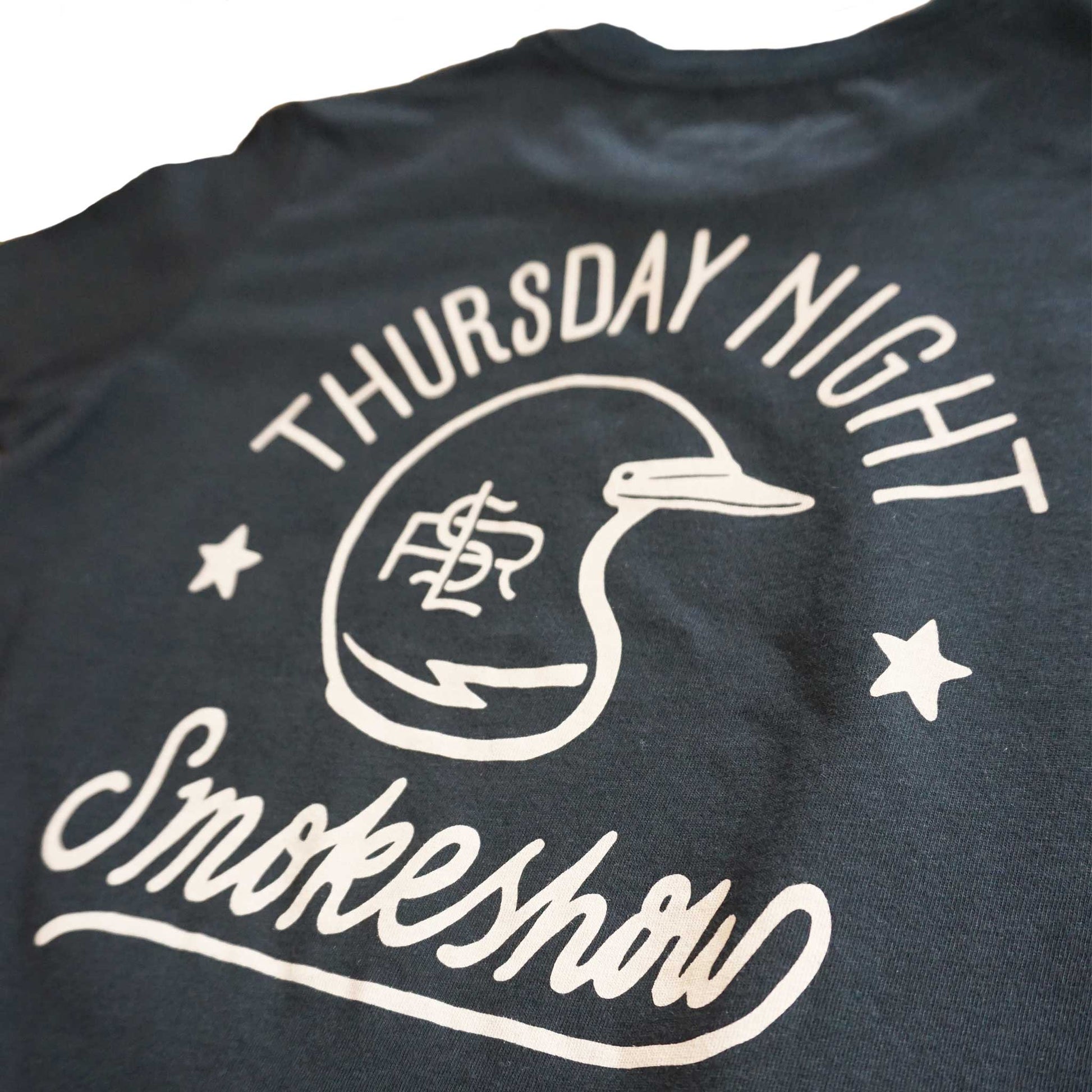 Close up of Youth black short sleeve graphic tees shirt back image of words Thursday Night Smokeshow with a vintage moto helmet with lightning bolt and LSR branding. Shirt is black and graphic is taupe in water based ink. 